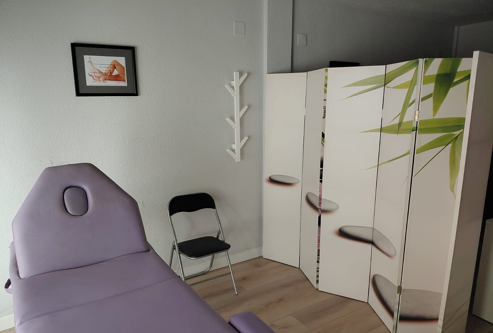 Sala de masajes de la consulta de Castellón, con camilla y biombo